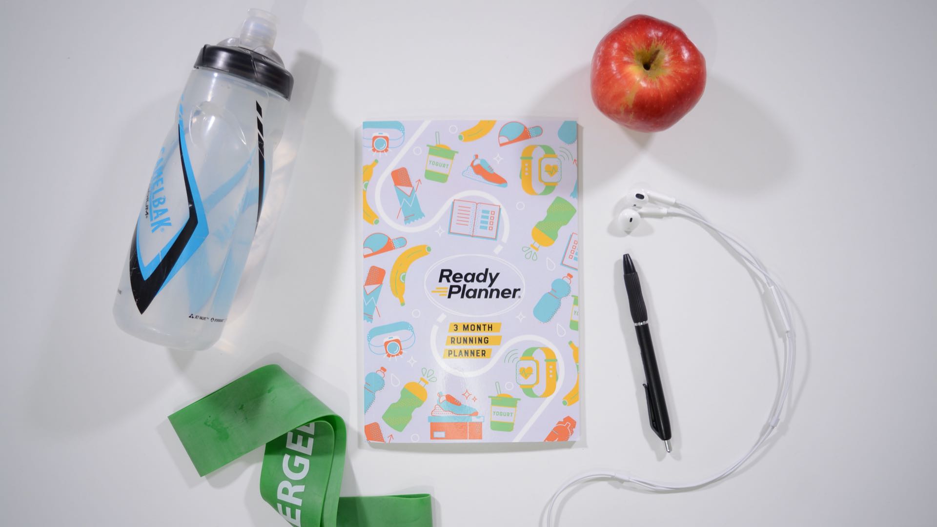 Top down view of planner with water bottle, headphones, and an apple